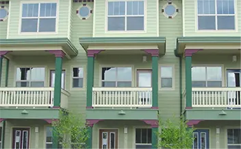A modern green apartment building with balconies and round windows